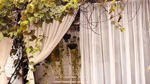 Un bâtiment blanc avec un rideau blanc et un banc.