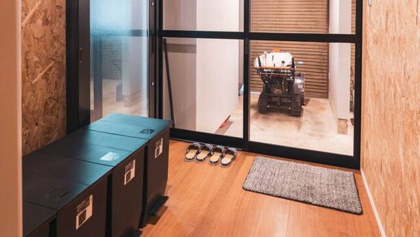 A compact room with a wooden ceiling, a sliding glass door leading to another room, a small bench, and a pair of slippers on the floor. - Luxe 6-bedroom Ski Lodge Myoko Kogen (Myoko)