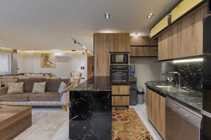 Eine moderne Küche mit Holzschränken, einer schwarzen Marmorarbeitsplatte und eingebauten Geräten.