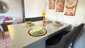 En matplats med ett ljusblått bord, svarta stolar och en vas med en solros. Det finns dekorativa väggdekorationer och en spegel på väggen.