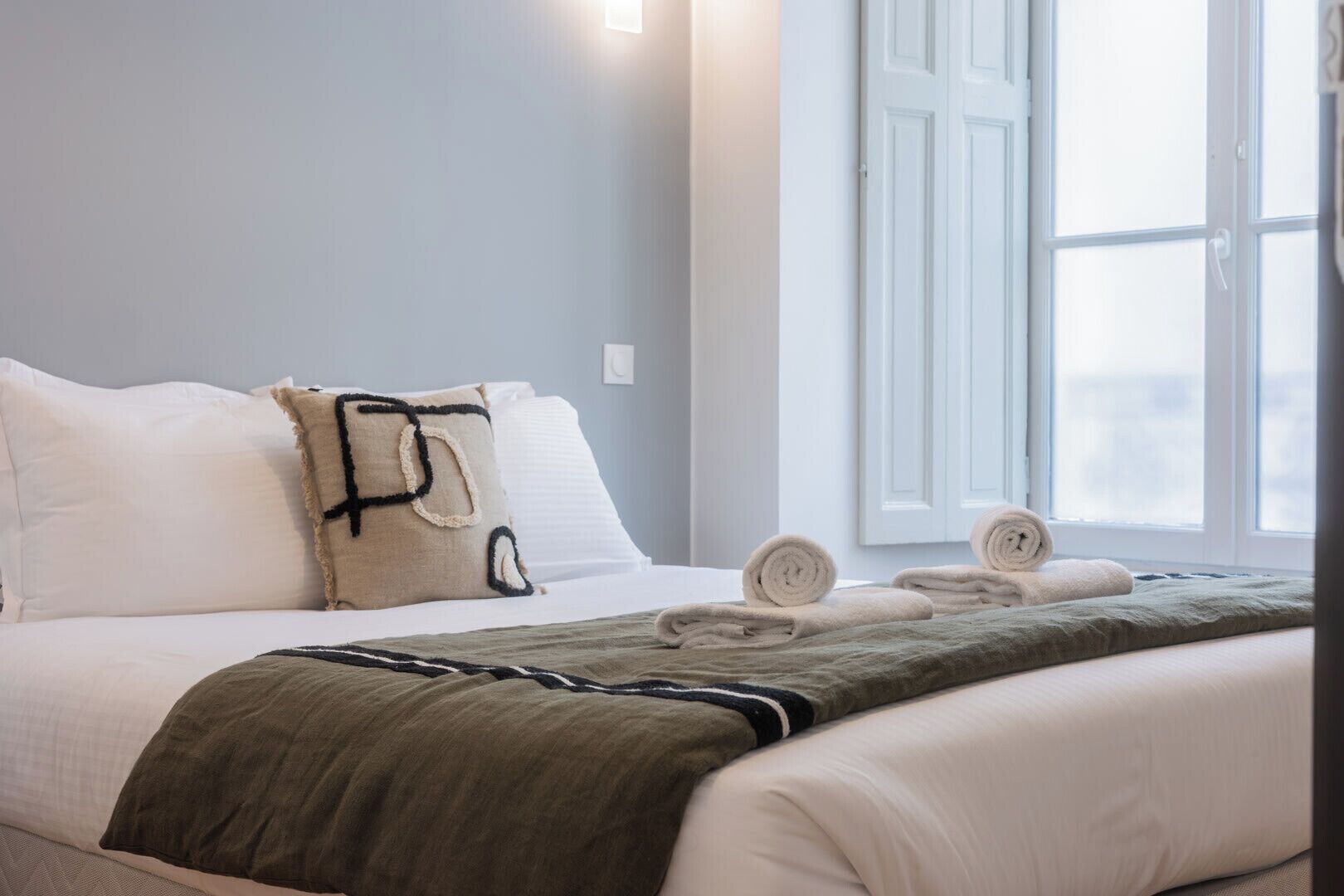 Ein Hotelzimmer mit Bett, Kissen, Decke und Handtüchern.