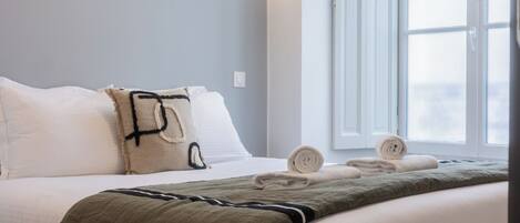 Una habitación de hotel con cama, almohadas, manta y toallas.