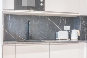 A kitchen with a Bosch microwave, a modern faucet, a toaster, and a coffee maker on a marble countertop. - Luxury 3-bedroom apartment in hyper centre, air con, lift (Bordeaux)