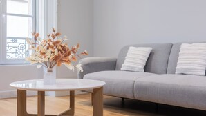 A modern living room with a grey sofa, white cushions, a round wooden coffee table, and a vase with dried flowers. - Luxury 3-bedroom apartment in hyper centre, air con, lift (Bordeaux)