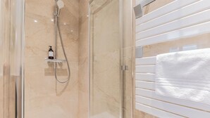 A modern bathroom with a glass shower enclosure, a white towel rack, and a marble floor. - Luxury 3-bedroom apartment in hyper centre, air con, lift (Bordeaux)