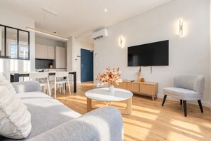 A modern living room with a sofa, coffee table, and a flat-screen TV mounted on the wall. - Luxury 3-bedroom apartment in hyper centre, air con, lift (Bordeaux)