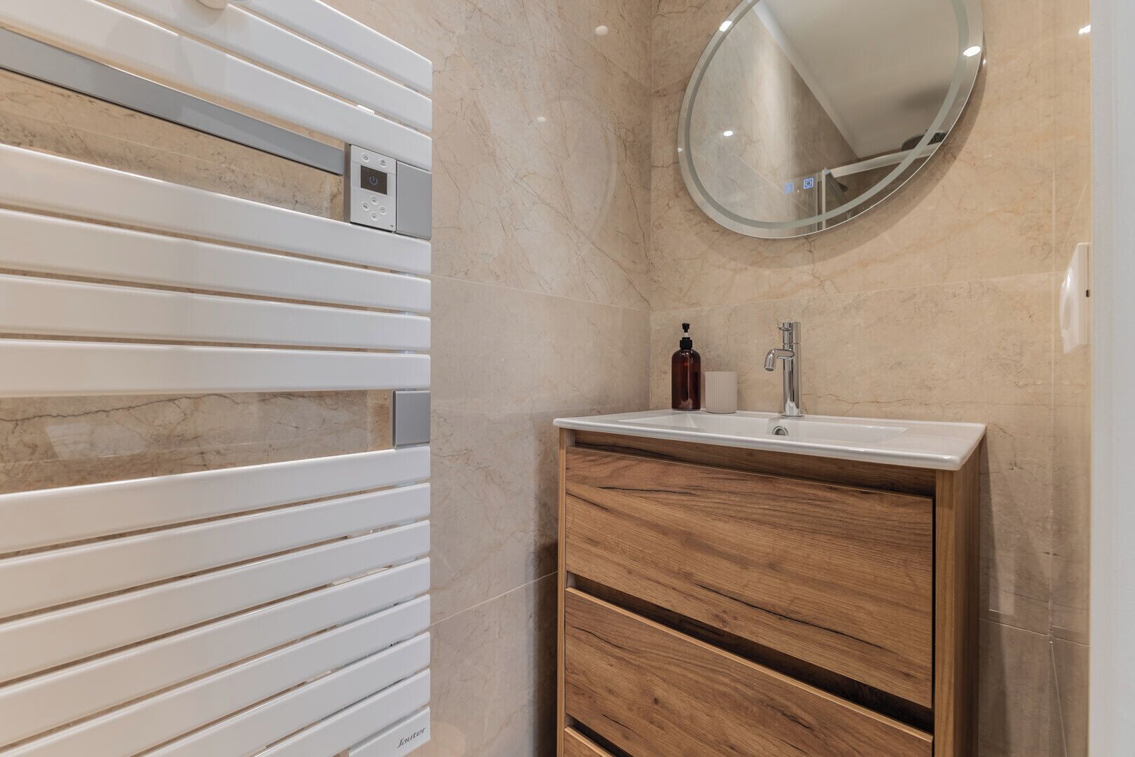 Un baño con tocador blanco, espejo y toallero de pared.