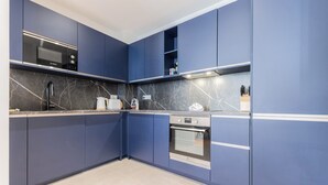 A modern kitchen with blue cabinets, a Bosch microwave, a built-in oven, and a marble backsplash. - Luxury 3-bedroom apartment in hyper centre, air con, lift (Bordeaux)