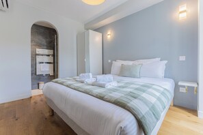 A hotel room with a bed, a wooden floor, a wall-mounted towel rack, and a light fixture. - Luxury 3-bedroom apartment in hyper centre, air con, lift (Bordeaux)