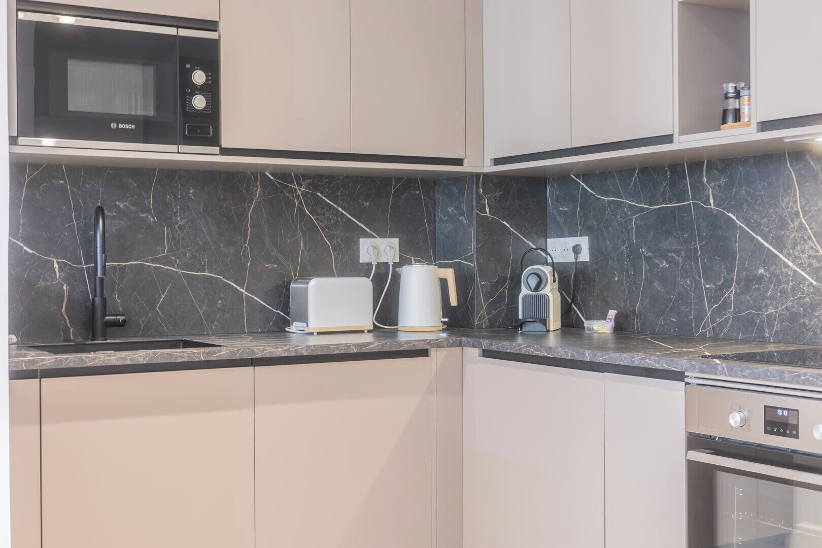 A modern kitchen with a Bosch microwave, a toaster, a kettle, and a coffee maker on the counter.