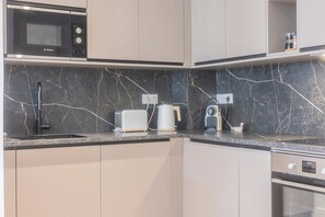 A modern kitchen with a Bosch microwave, a toaster, a kettle, and a coffee maker on the counter. - Luxury 3-bedroom apartment in hyper centre, air con, lift (Bordeaux)