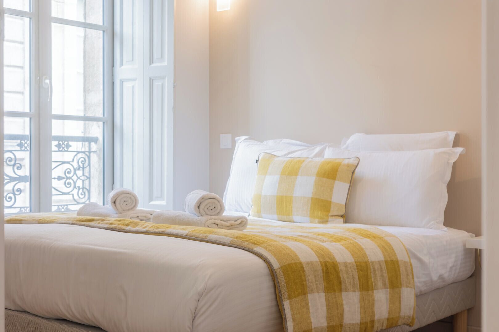 A hotel room with a bed, pillows, a blanket, and a window with a view.
