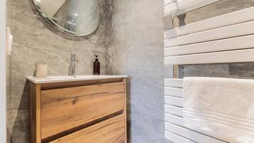 A bathroom with a wooden vanity, a mirror, a sink, and a towel rack.