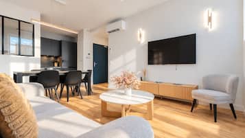 A modern living room with a sofa, coffee table, and a TV mounted on the wall.