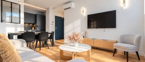 A modern living room with a sofa, coffee table, and a TV mounted on the wall.