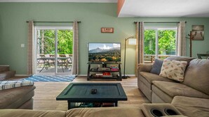 Ein Wohnzimmer mit einer Couch, einem Couchtisch, einem Fernseher und einem Schild mit der Aufschrift 'SEE'.