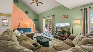Ein Wohnzimmer mit einer Couch, einem Couchtisch, einem Fernseher und einem Deckenventilator.