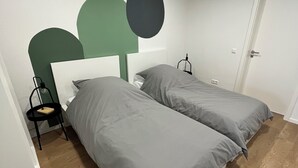 Une pièce avec deux lits, une chaise, un bureau et une porte.