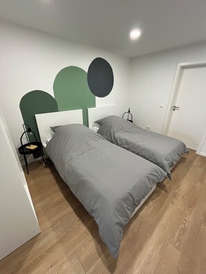 A room with two beds, a chair, a desk, and a door. - Renovated vacation apartment / commuter apartment in a quiet location with parking facilities (Bissingen an der Teck)