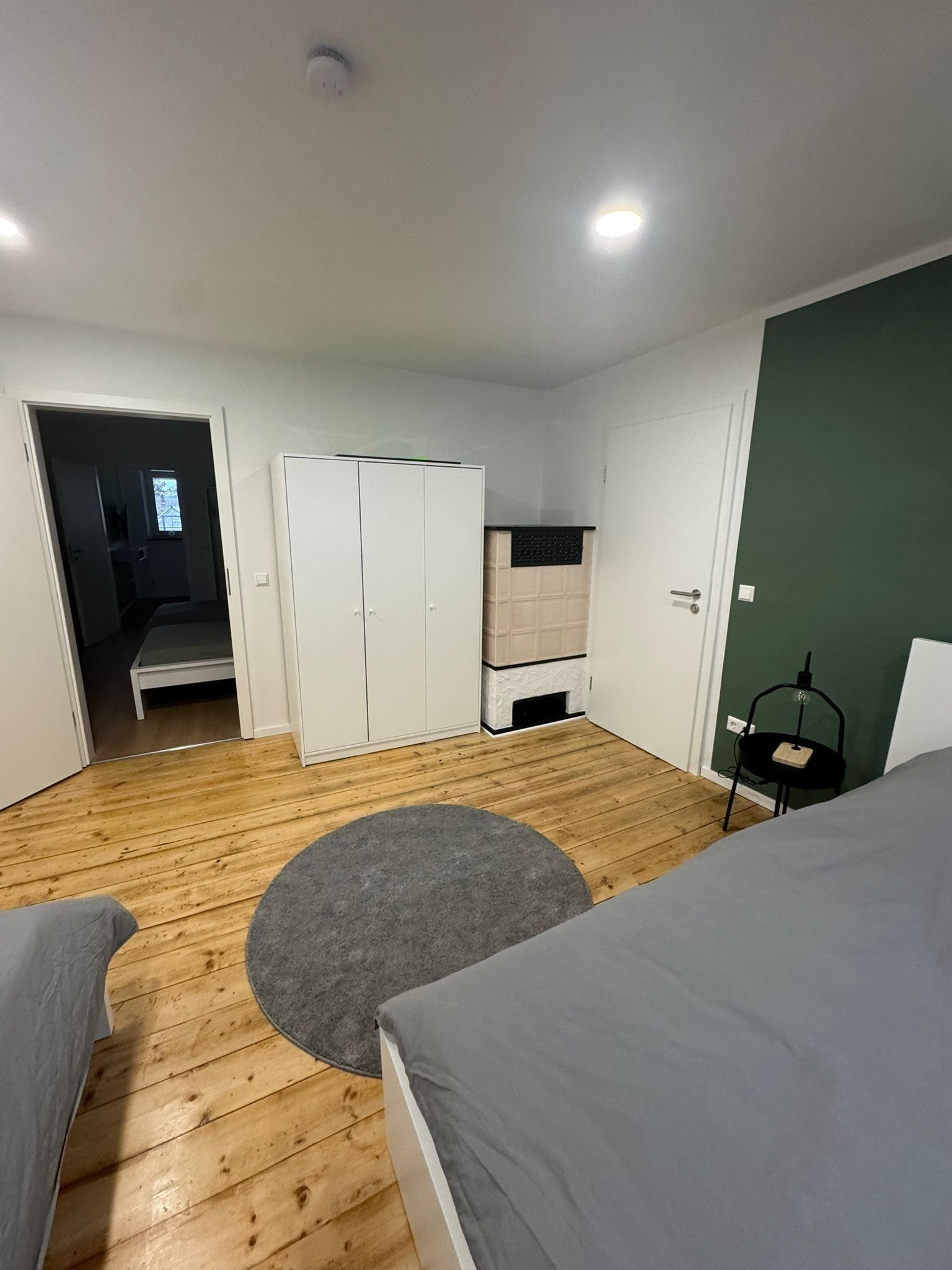 A bedroom with a bed, a wardrobe, a desk, and a chair.