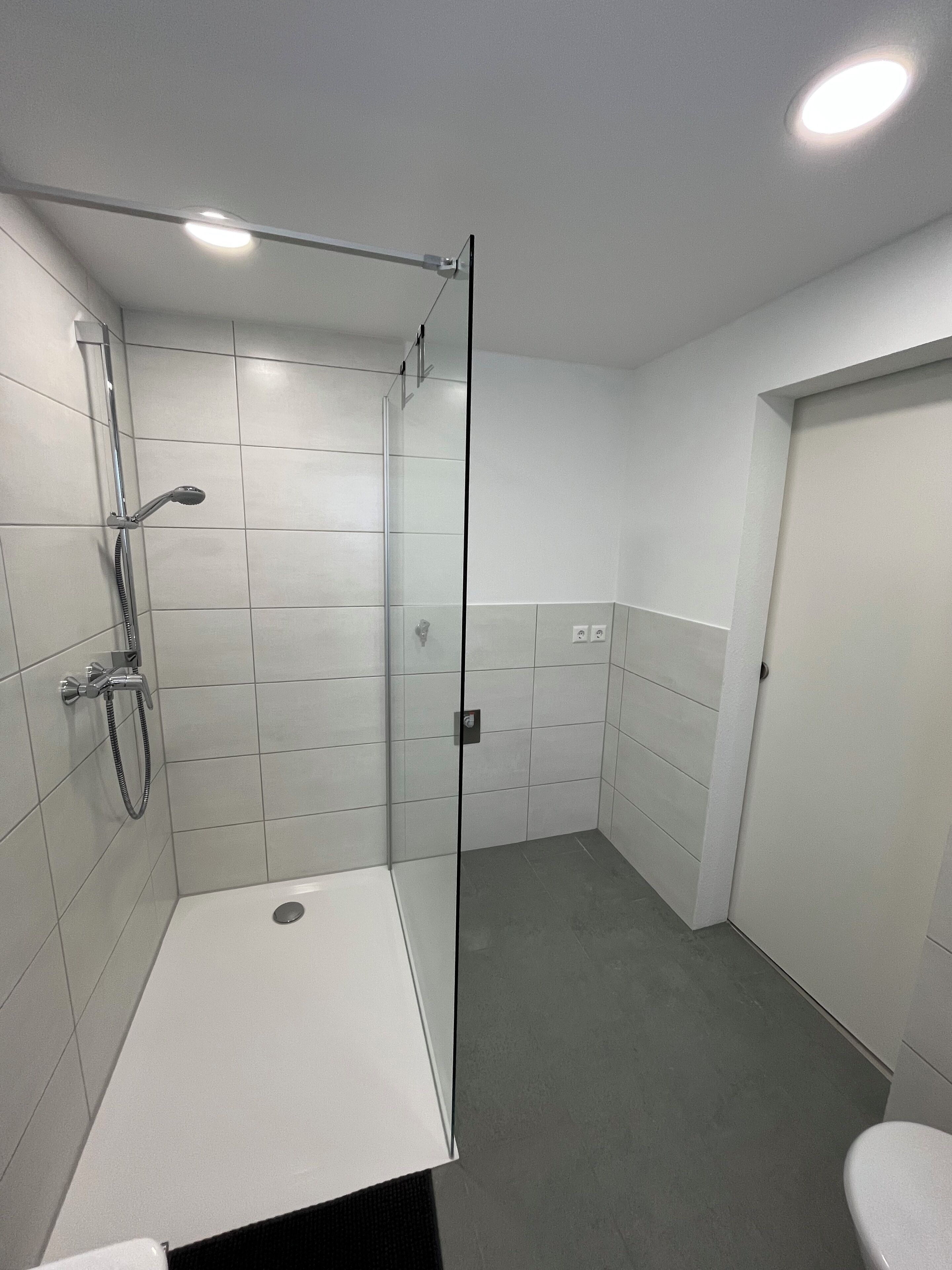 Un baño moderno con ducha, inodoro y mampara de vidrio.