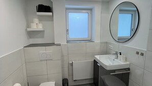 Une salle de bain moderne avec des toilettes, un lavabo et un miroir.