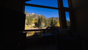 A room with a large window offering a view of a mountainous landscape with trees and a clear sky.