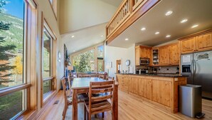 A spacious kitchen with wooden cabinets, a stainless steel refrigerator, and a dining area with a large table and chairs.