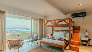 A bedroom with a large window, a wooden bed, a chair, a small table, and a nightstand.
