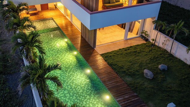 A modern two-story house with a swimming pool, a wooden deck, and a well-maintained lawn.