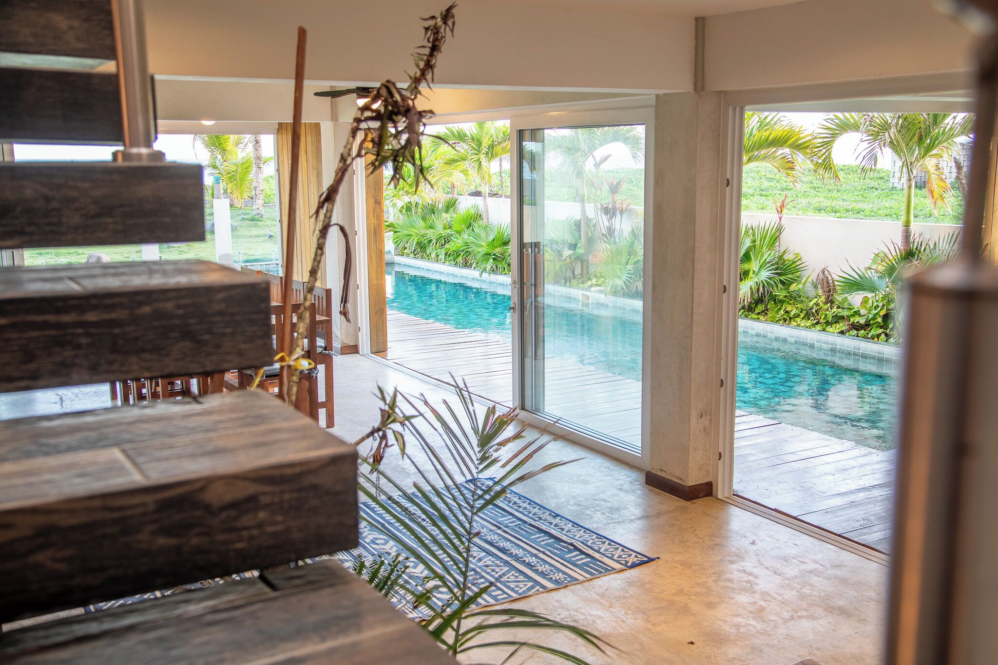 A modern interior with a pool view, wooden flooring, and a staircase.