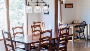 A dining area with a wooden table and chairs, a chandelier, and a view of the outdoors. - Hot tub, great views, huge deck. Near town, RMNP (Estes Park)