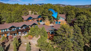 A lodge with multiple cabins, surrounded by dense forest and mountains in the background.