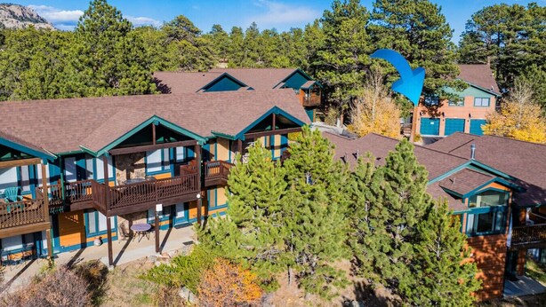A lodge with multiple wooden cabins, balconies, and a mountainous backdrop.
