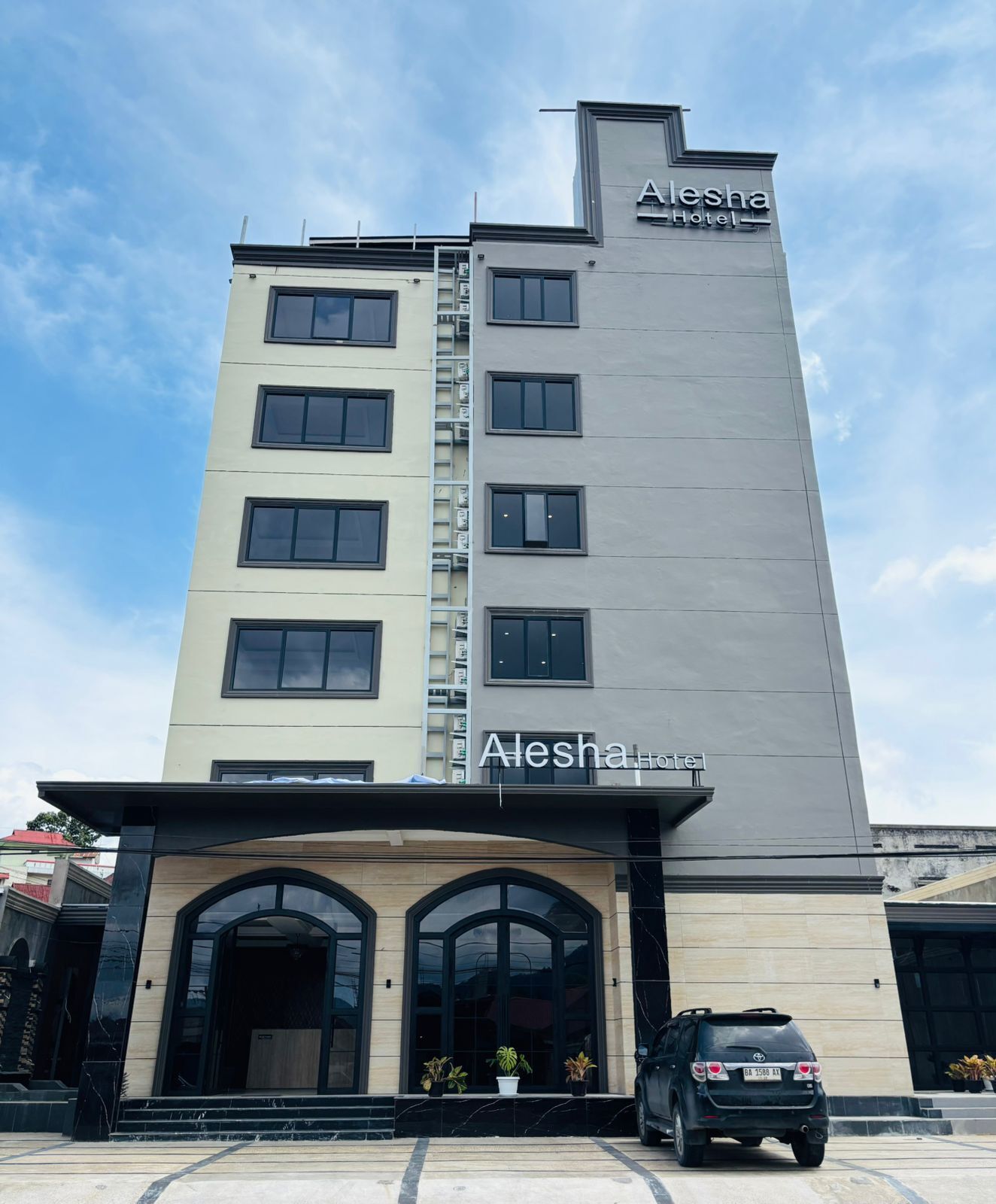 Un edificio de hotel alto con un cartel que dice "Alesha Hotel" en la fachada.