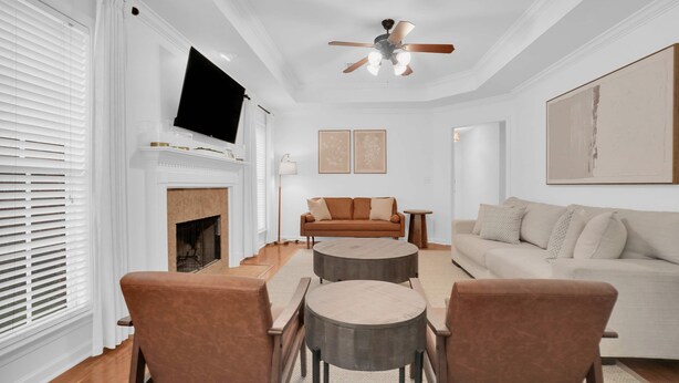 Ein Wohnzimmer mit Kamin, einem darüber montierten Fernseher, einem Deckenventilator und zwei Sofas.