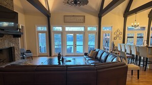 A spacious living room with a stone fireplace, a large leather sectional sofa, and a dining area with a bar. - Enjoy beautiful sunsets at Blue Bird Cove on Lewis Smith Lake with private dock. (Crane Hill)