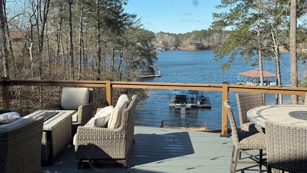 A deck with wicker furniture, a view of a lake, and a dock with boats. - Enjoy beautiful sunsets at Blue Bird Cove on Lewis Smith Lake with private dock. (Crane Hill)