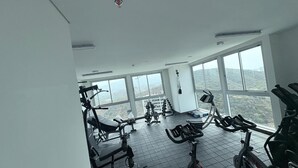 Ein Fitnessstudio mit unterschiedlicher Trainingsausstattung, großen Fenstern und Blick ins Freie.