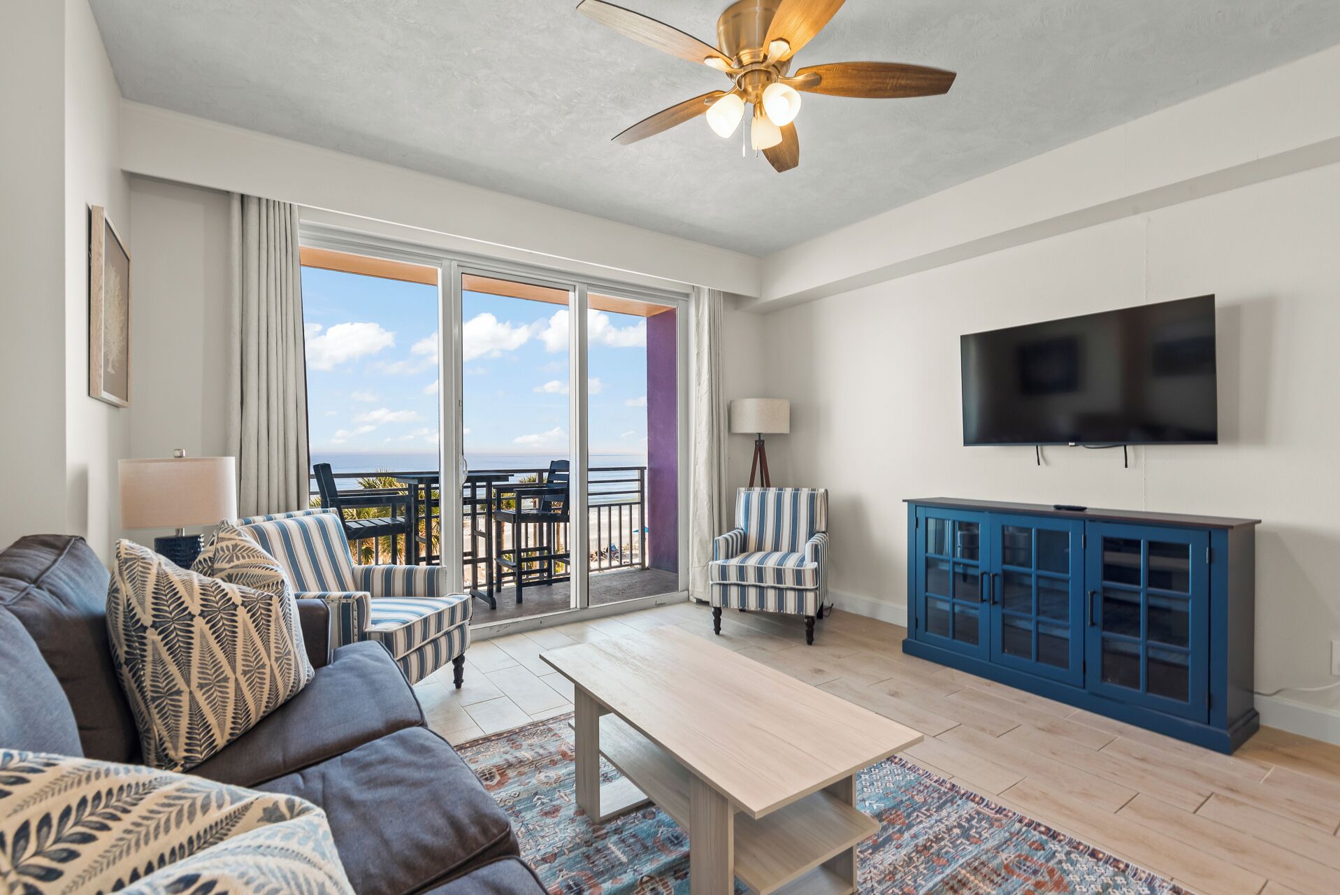 Un salon comprenant un canapé, des fauteuils, une table basse, un téléviseur et un balcon avec vue.