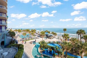 Een resort met een zwembad, palmbomen en uitzicht op de oceaan.