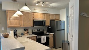 Une cuisine moderne avec des meubles en bois, des appareils électroménagers en acier inoxydable et des luminaires suspendus.
