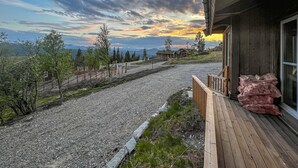 A gravel driveway leading to a wooden deck with a view of a mountainous landscape and a sunset. - Nice home in Gålå with sauna (Gålå)