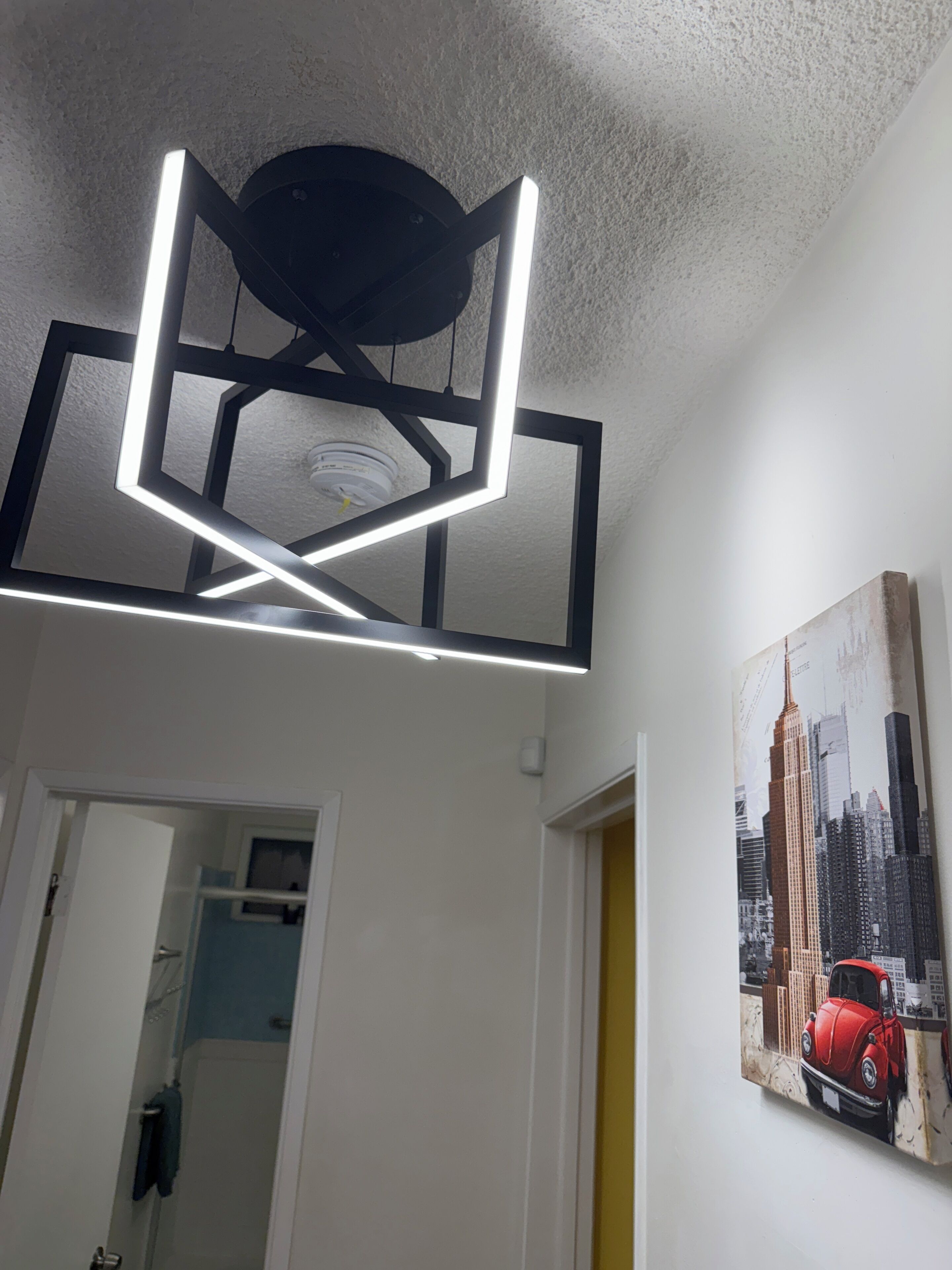 Un luminaire de plafond moderne aux formes géométriques, comprenant un spot encastré.