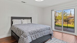 Een slaapkamer met een bed, een plafondlamp, een raam en uitzicht op het omliggende landschap.