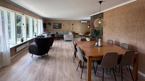 Un comedor amplio con una mesa y sillas de madera, un sofá y un ventanal con cortinas.