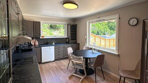 Una cocina moderna con comedor, que incluye lavavajillas, estufa y una mesa redonda con sillas.