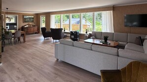 Una sala de estar amplia con un sofá grande de color gris, una mesa de centro de madera y un comedor con mesa y sillas.