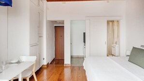 Un dormitorio con cama, escritorio y silla. Hay una puerta que da a un baño.