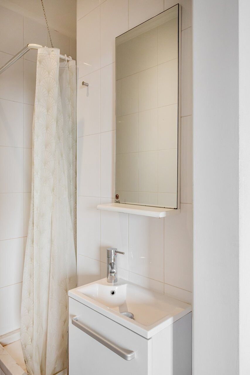 Een badkamer met een douche, een wastafel en een spiegel.